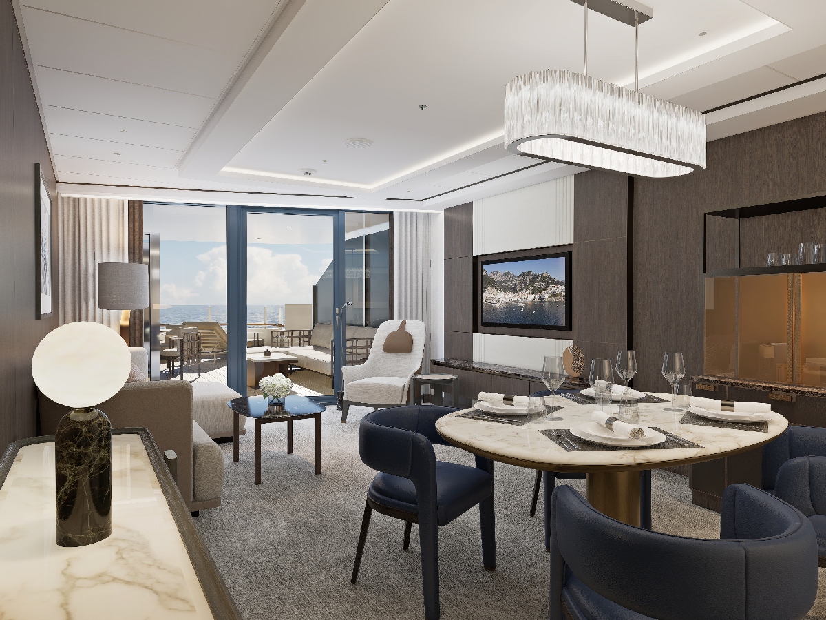 A luxurious yacht suite interior features an open-plan living and dining area with a round dining table surrounded by navy blue upholstered chairs, complemented by a contemporary living space with neutral-toned furniture and a large rectangular crystal chandelier overhead. Floor-to-ceiling windows and glass doors provide expansive ocean views and access to a private terrace, showcasing the sophisticated modern design typical of the Ritz-Carlton Yacht Luminara's premium accommodations.